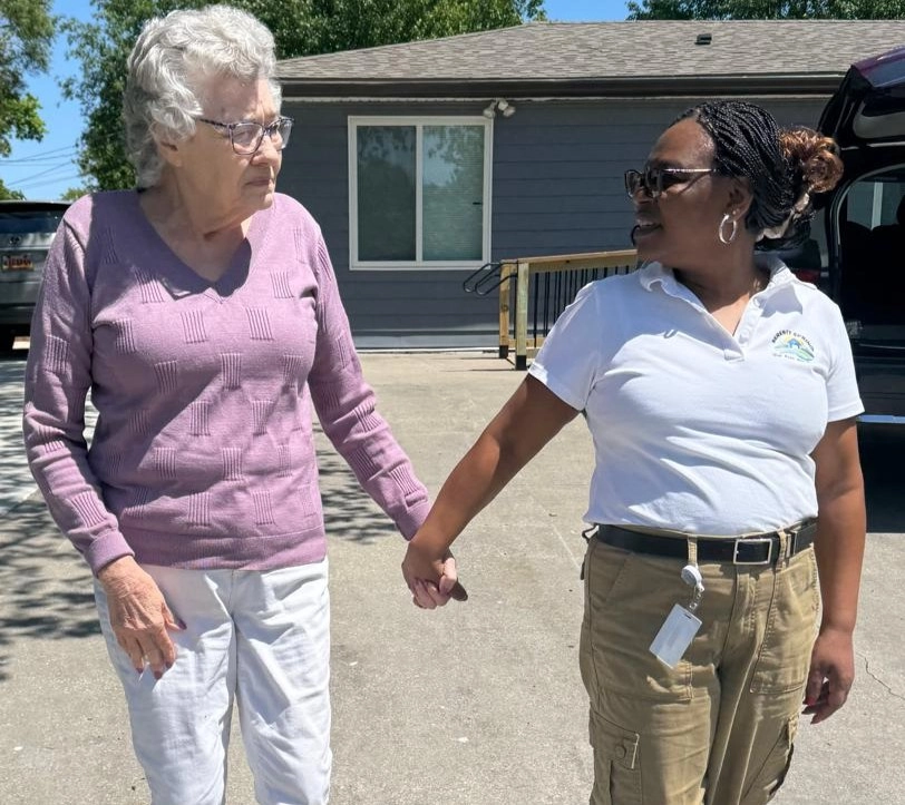 Caregiver Walking Outdoors With A Senior Resident Holding Hands For Support And Companionship
